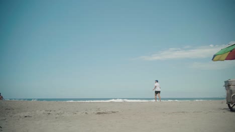 Hombre-Tirando-De-Un-Puesto-De-Helados-Con-Coloridas-Sombrillas-A-Lo-Largo-De-La-Union-Beach,-Filipinas