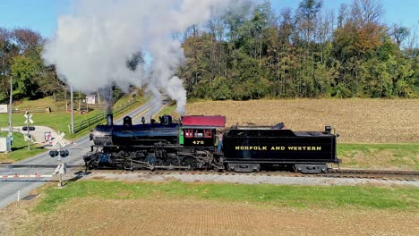 An-Aerial-View,-of-an-Antique-Steam-Freight-Passenger-Train-Blowing-Smoke-as-it-Slowly-Travels-on-an-Autumn-Day