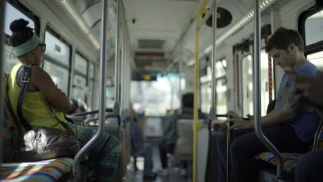 A-video-captures-diverse-passengers-aboard-a-moving-bus-in-Los-Angeles,-California,-each-engrossed-in-their-mobile-devices,-representing-various-walks-of-life