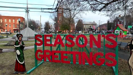 Seasons-Greetings-Sign-on-grass-field-of-park-in-small-american-town