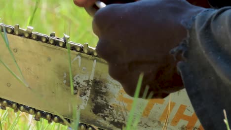 Extreme-close-up-shot-of-a-Black-man-sharpen-a-chainsaw-with-a-file