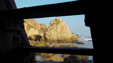 Looking-through-the-stairs-on-El-Matador-Beach-at-golden-hour-in-Malibu,-California