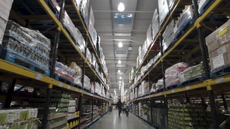 Warehouse-aisle-in-Costco-with-products-on-shelves-and-shoppers-in-distance,-interior,-artificial-lighting