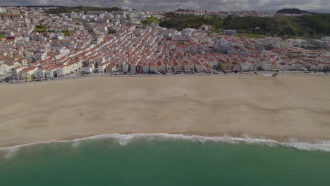 Luftaufnahme-Eines-LKWs-Mit-Einem-Atemberaubenden-Panorama-Von-Nazare,-Portugal-Mit-Seinem-Berühmten-Strand