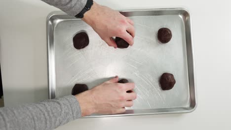 Person-prepare-dark-chocolate-cookie-dough-shapes-on-metal-cooking-sheet
