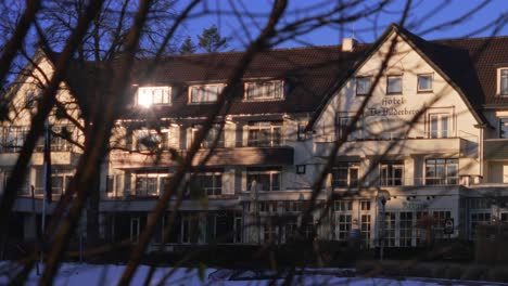 Fixed-shot-of-Bilderberg-hotel-accomodation-seen-through-trees-with-sunlight-reflection-in-window