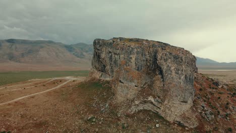 Ascending-aerial-view-behind-rock-formation-to-reveal-mountain-range