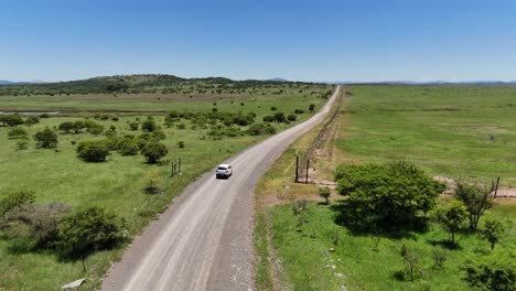 White-SUV-drives-through-a-gate-in-KwaZulu-Natal,-South-Africa-aerial