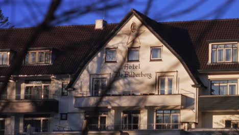 Handheld-closeup-of-Bilderberg-hotel-facade-seen-trough-branches-of-trees