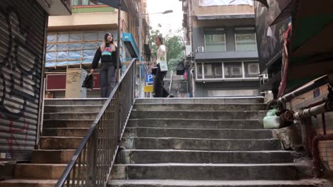 Two-women-walk-next-to-some-stairs-in-Sheung-Wan,-Hong-Kong