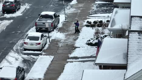 Aerial-establishing-shot-of-a-child-shoveling-snow