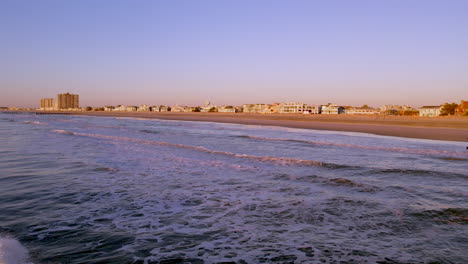Flug-über-Den-Ozean-In-Richtung-Jersey-Shore-Beach-Im-Morgengrauen-Mit-Häusern-Im-Hintergrund