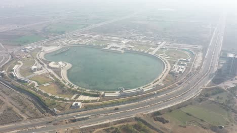 Rajkot-Atal-lake-drone-view-many-big-big-lake-and-many-vehicles-are-going-on-the-road,-Rajkot-New-Race-Course,-Atal-Sarovar