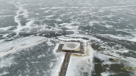 Ventes-horn-lighthouse-on-a-frozen-coastline-in-lithuania,-surrounded-by-ice-patterns,-aerial-view