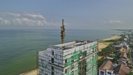 Negombo,-Sri-Lanka:-Eine-V8-Drohne-Fliegt-Aus-Der-Luft-Um-Das-Dach-Eines-Neuen-Strandhotelgebäudes,-Das-Derzeit-Am-Touristischen-Wahrzeichen-Browns-Beach-Mit-Meerblick-Gebaut-Wird-–-Aufgenommen-Mit-Mavic-3-Cine-–-April-2023