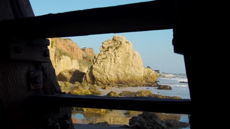 Looking-through-the-stairs-on-El-Matador-Beach-at-golden-hour-in-Malibu,-California