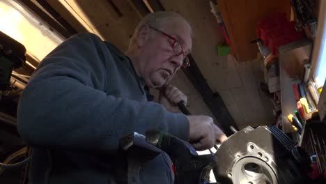 Senior-caucasian-worker-uses-hand-honing-machine-on-engine-block