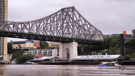 Ferry's-passing-on-the-Brisbane-River-in-front-of-Howard-Smith-Wharves-with-The-Story-Bridge-viewed-from-New-Farm-River-Walk