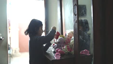 Side-view-of-young-girl-playing-with-her-doll-with-blurred-background