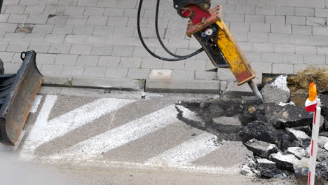 Excavator-hydraulic-hammer-breaking-asphalt-road-surface-on-reconstruction-site