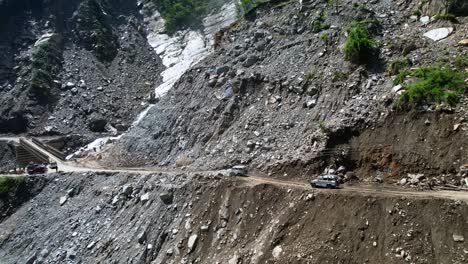 Off-Road-Jeeps-Drive-on-Steep-Narrow-Mountain-Dirt-Road-Passing-Rupse-Falls-in-Central-Nepal---Aerial-Panning