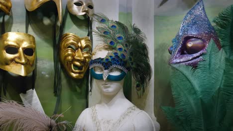 Peacock-feather-mask-and-golden-faces-at-Ca'-Macana,-Venice-Italy