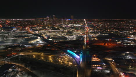 Denver-downtown-i25-highway-traffic-aerial-drone-cinematic-anamorphic-snowy-winter-evening-dark-night-city-lights-landscape-Colorado-Mile-High-DU-Metro-state-Ball-arena-forward-pan-reveal-motion