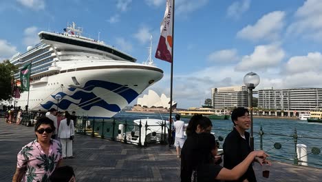 Cruise-ship-docked-at-Sydney-Harbor-with-people-and-Opera-House-in-view,-clear-day