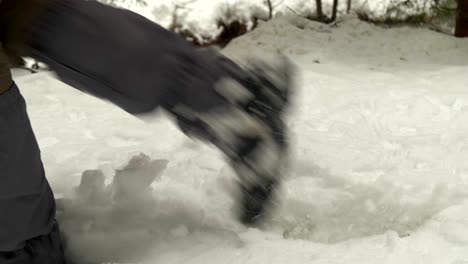 Leg-detail-view-of-hikers-stepping-in-thick-snow-near-a-mountain-river