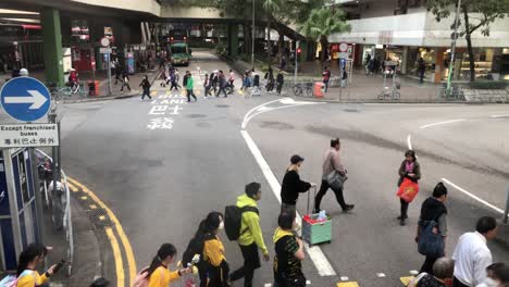 People-cross-the-road-next-tot-he-bus-terminal-in-Tai-Po,-Hong-Kong