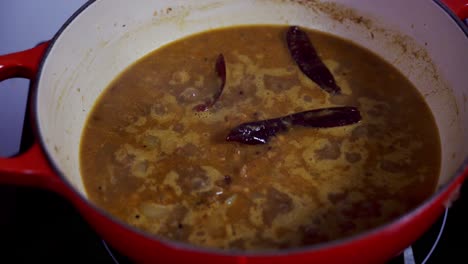 Curry-In-Einem-Topf-Köcheln-Lassen-Und-Mit-Drei-Roten-Chilischoten-Darin-Kochen,-Um-Ihm-Etwas-Schärfe-Zu-Verleihen
