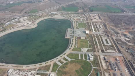 Cámara-Del-Amanecer-Con-Vista-De-Drones-Del-Lago-Rajkot-Atal-Que-Muestra-El-Gran-Lago-Y-Muchos-Chakras-Ashoka-Alrededor,-El-Nuevo-Hipódromo-De-Rajkot,-Atal-Sarovar