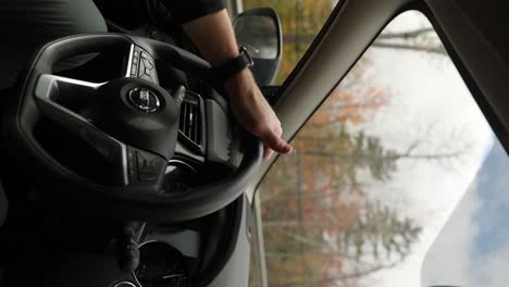 Driver's-Hand-On-Steering-Wheel-Driving-a-Nissan-Car-Through-The-Forest-During-Fall-In-New-Hampshire