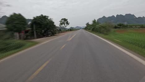 Car-overtaking-bike-rider-in-Vietnam,-time-lapse-POV-view