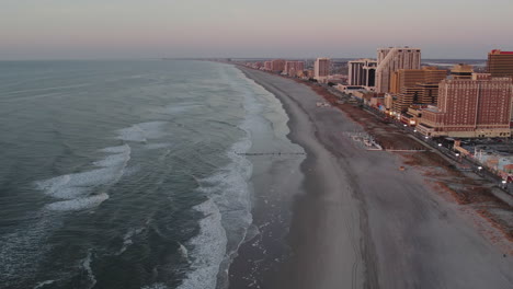 Drone-flying-along-Atlantic-City-coast-towards-the-beaches-showing-casinos-during-blue-hour