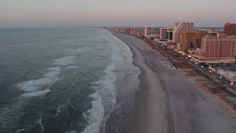 Drohne-Fliegt-Entlang-Der-Küste-Von-Atlantic-City-In-Richtung-Der-Strände-Und-Zeigt-Casinos-Während-Der-Blauen-Stunde