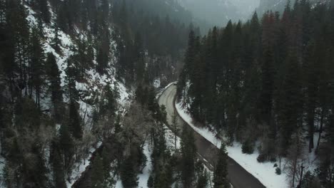 Car-Driving-In-American-Fork-Canyon-As-Snow-Falls,-Aerial-Shot