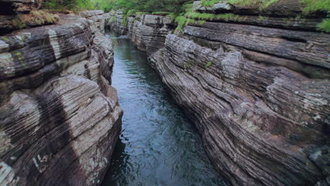 Rushing-water-through-the-layered-rock-canyon-of-Cajones-de-Chame,-Panama,-lush-greenery-above