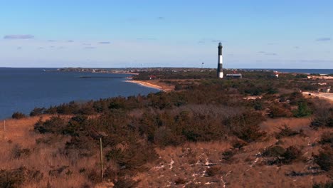 An-aerial-view-of-the-Fire-Island-Lighthouse-with-blue-skies-and-dry-winter-foliage