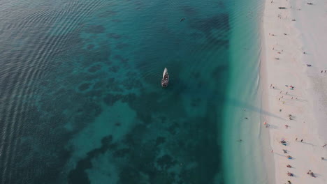 Tourists-boat-sails-near-the-nice-beach-of-Zanzibar,-summer-concept,-carefree-holiday,-Africa,-Tanzania