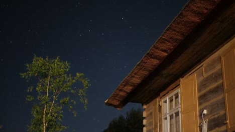 Timelapse-Del-Cielo-Nocturno-Con-árbol-Y-Techo-De-Paja-Antigua-Casa-Rústica-Y-Acogedora