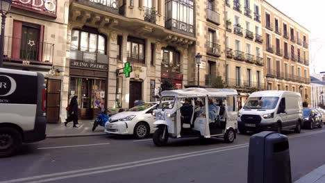 electric-tuk-tuk-in-Madrid-spain-driving-tourists-trough-busy-streets-in-city-center