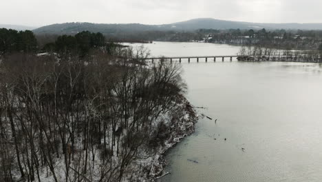 Lake-Sequoyah-in-winter-snowy-landscape,-view-of-bridge-in-distance,-cloudy-day