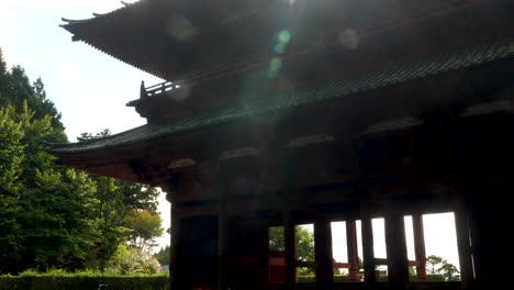 Koyasan-Daimon,-a-large-historical-gate-in-a-serene-forest-setting,-on-a-clear-day-with-lens-flare-in-shot