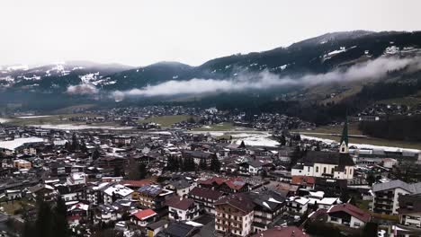 Foggy-Alps-and-Kirchberg-township-bellow,-aerial-view