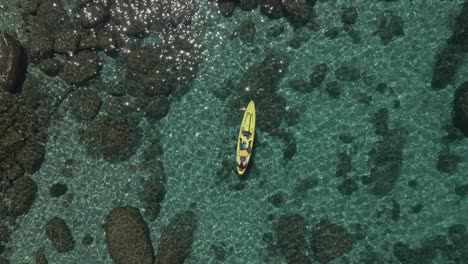 Aerial-shot-descending-over-a-man-sunbathing-on-a-kayak