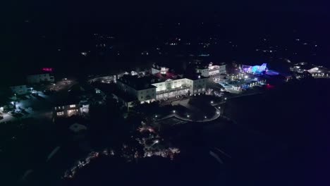 Bird's-eye-view-high-above-exquisite-luxury-hotel-grounds-at-night-in-secluded-mountain-town