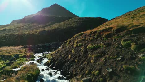 Aerial-drone-camera-flies-along-a-mountainous-brook