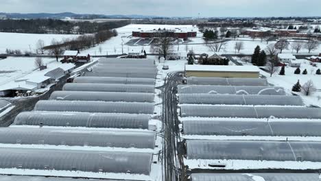 Rising-aerial-shot-of-greenhouses-covered-in-snow