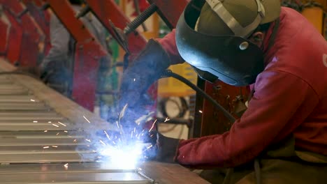 Welder-in-action-with-bright-sparks-flying,-wearing-protective-gear-in-an-industrial-setting,-close-up